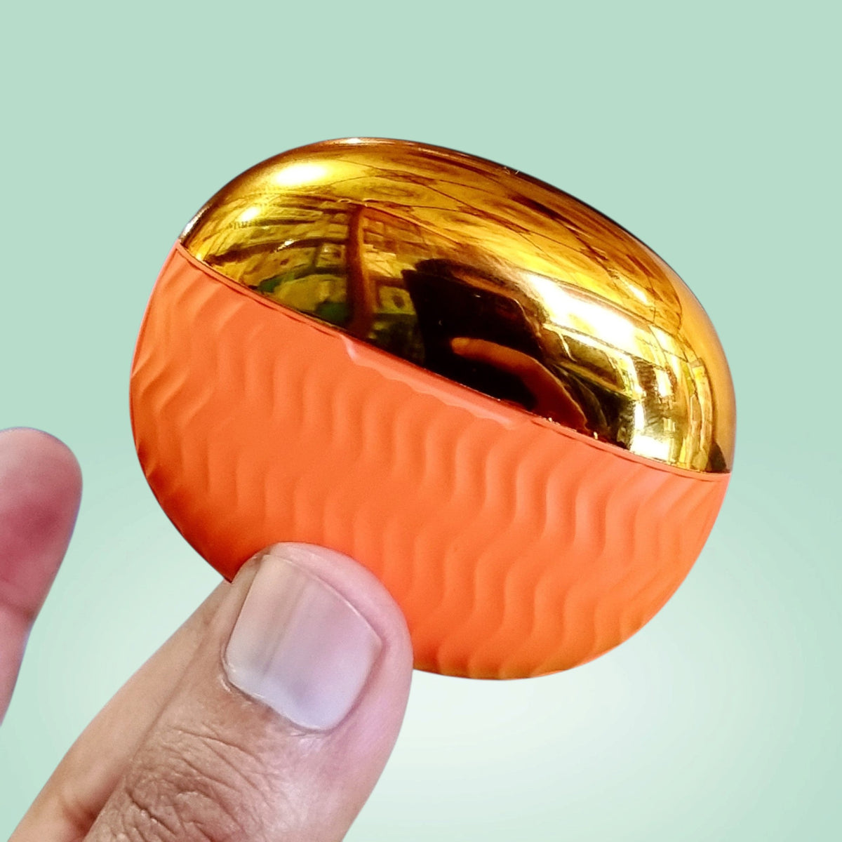 ADNAN MOBILE SHOP EarBuds 6 charging case with a metallic gold top and textured orange silicone base held in hand